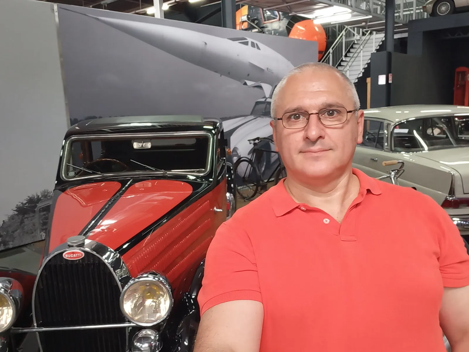 Sergey Raevsky next to a Bugatti in a car museum