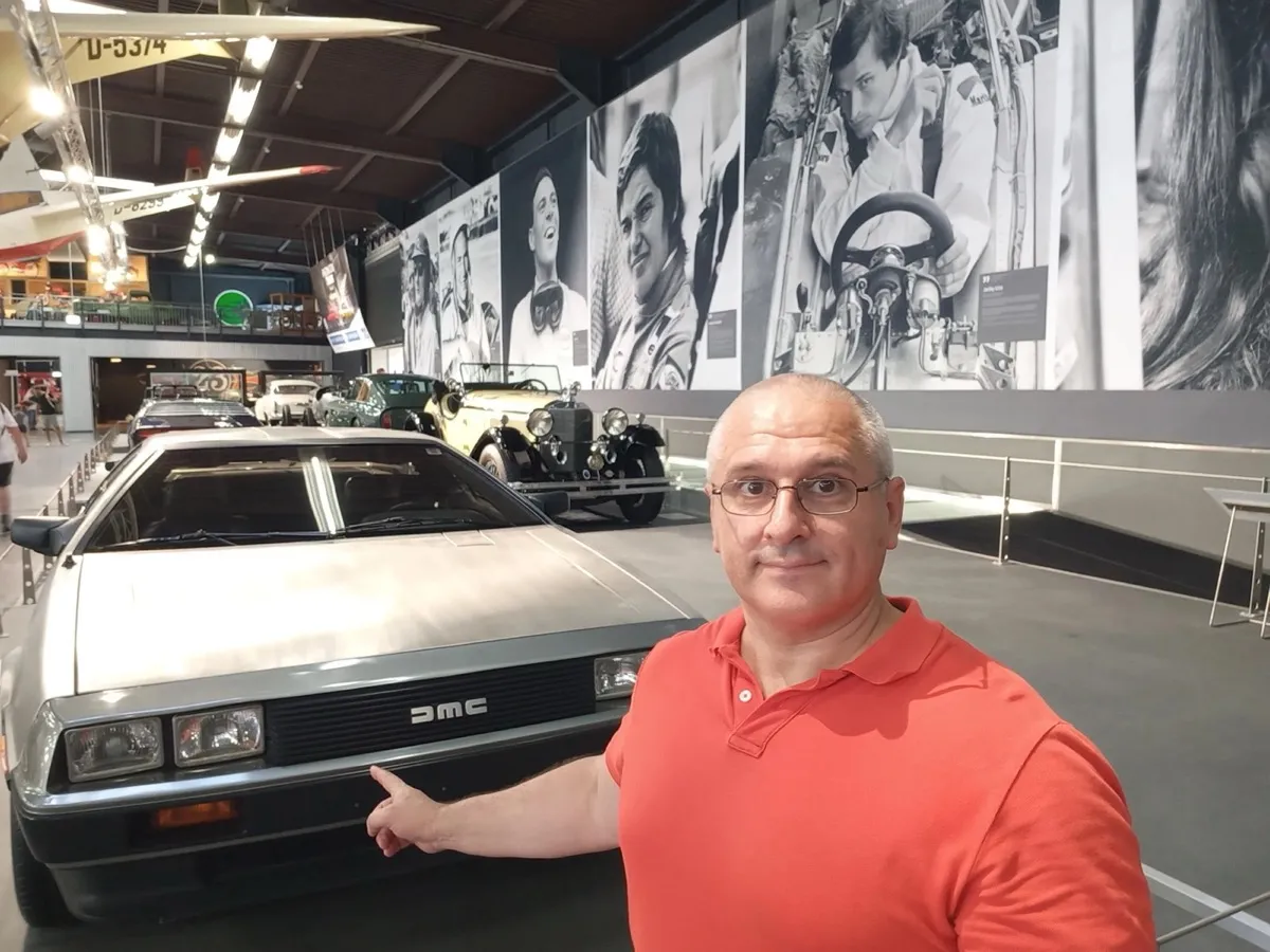 Sergey Raevsky next to a DeLorean at a car museum