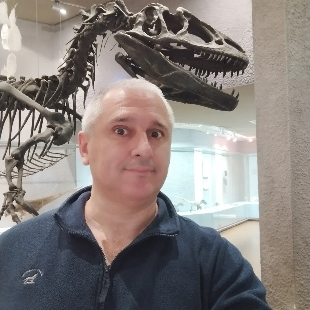 Sergey Raevsky next to a dinosaur at a museum